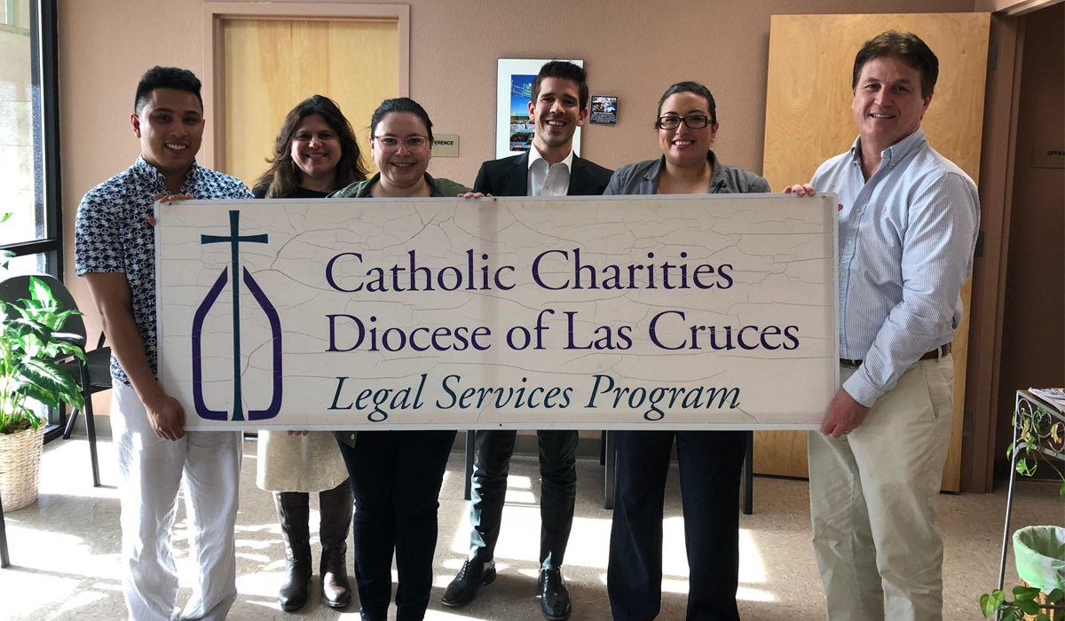 law student holding up a catholic charities banner in New Mexico